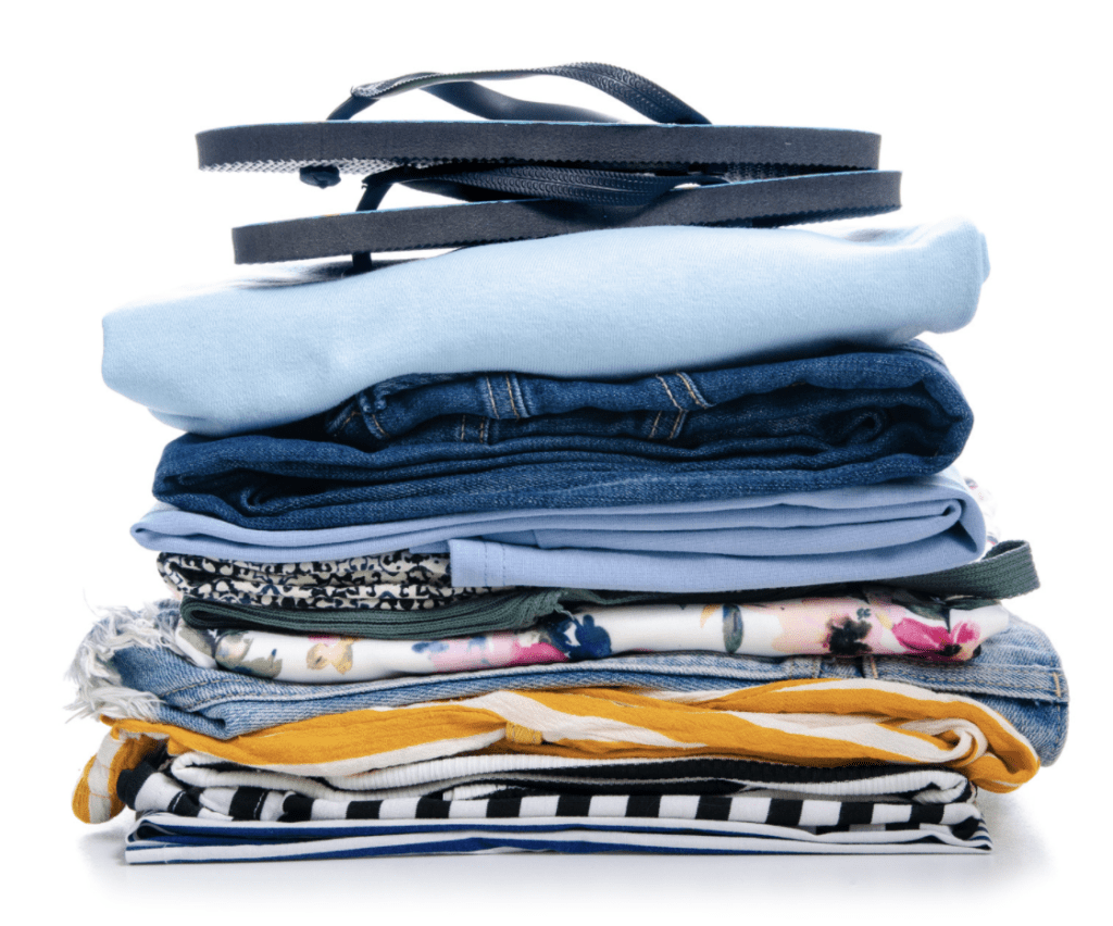 A stack of folded clothes, including jeans and various tops.