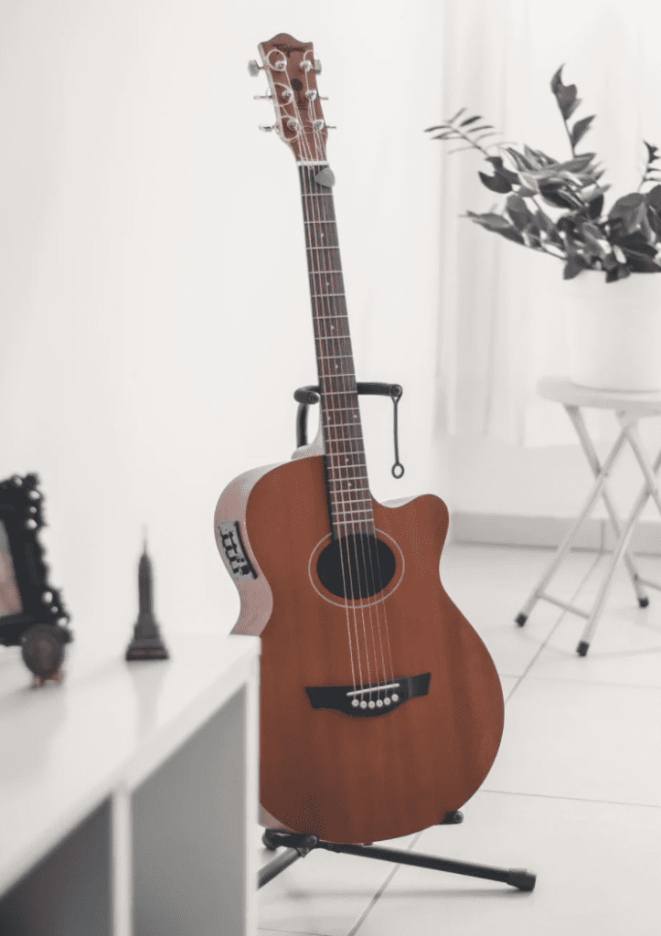 An acoustic guitar resting on a stand in a modern room with plants and minimal decor.