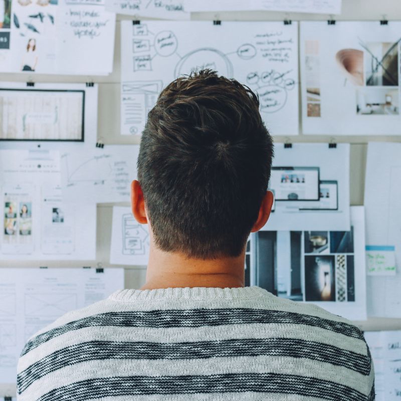 Man analyzing a wall covered in notes and business strategies for start-ups.