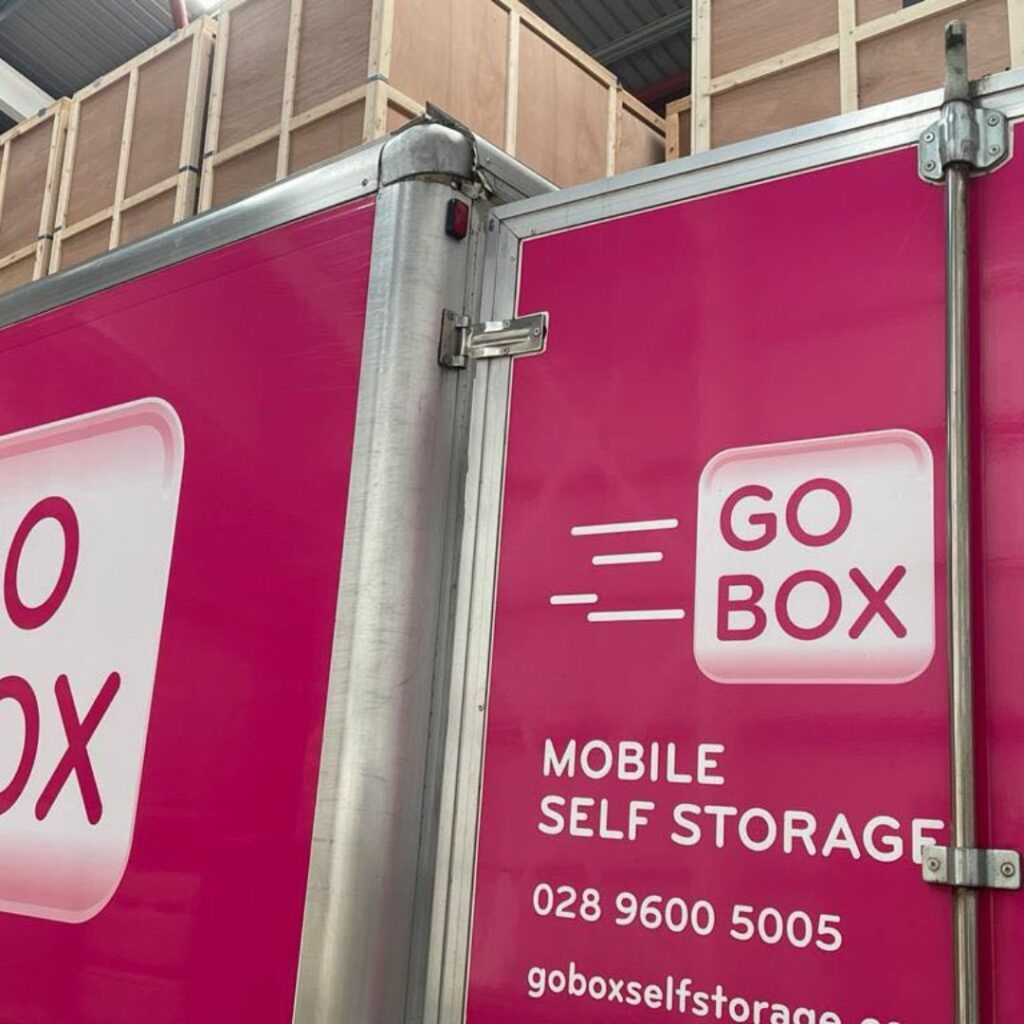A close-up view of a pink mobile self-storage unit with the branding "go box" on the side.