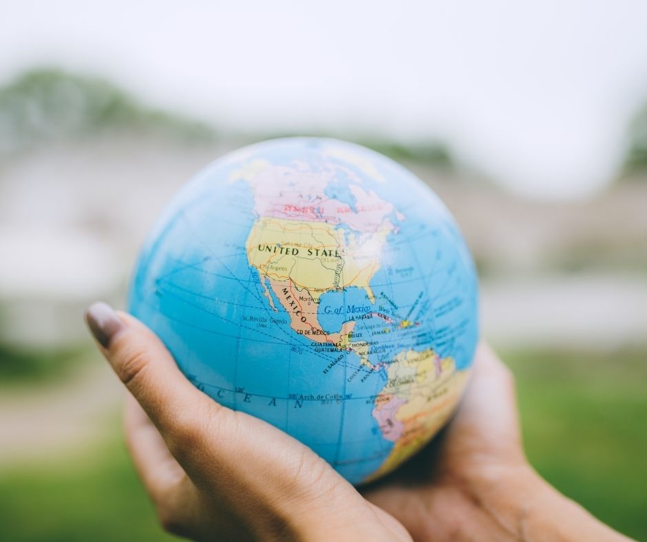 A person holding a small globe with focus on north america.
