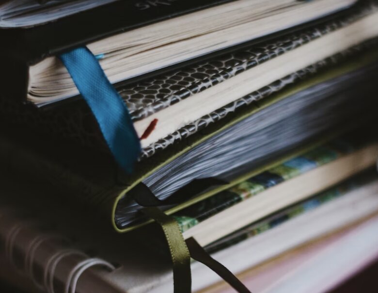 A stack of books with ribbon bookmarks.