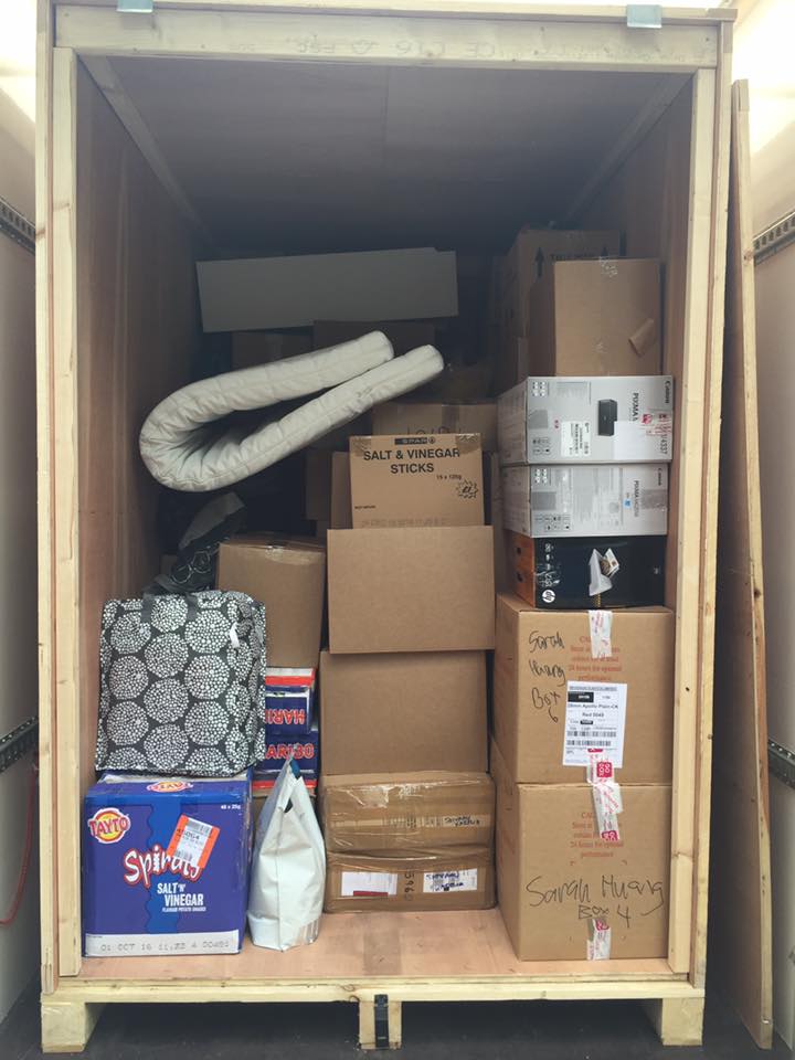A moving truck is partially filled with various items, including boxes, a mattress, and bags, indicating a household move in progress.