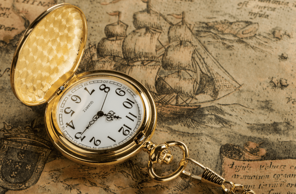 An open gold pocket watch rests on a vintage map.