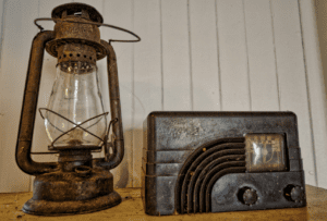 Vintage oil lantern and old-fashioned radio on a wooden surface with a white wall in the background.