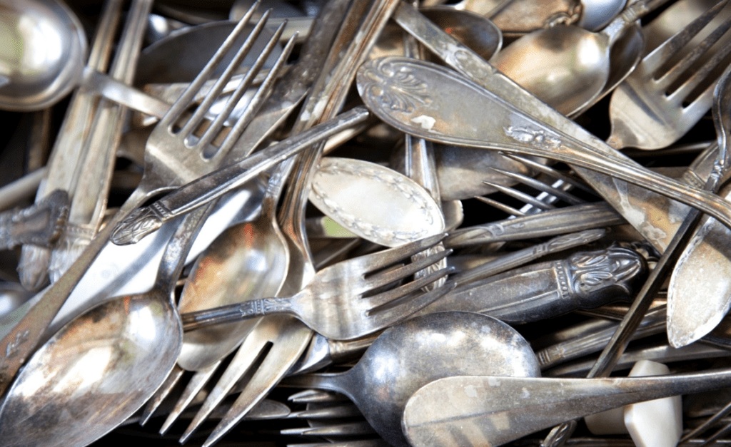 A pile of assorted, used silverware including forks, spoons, and knives.