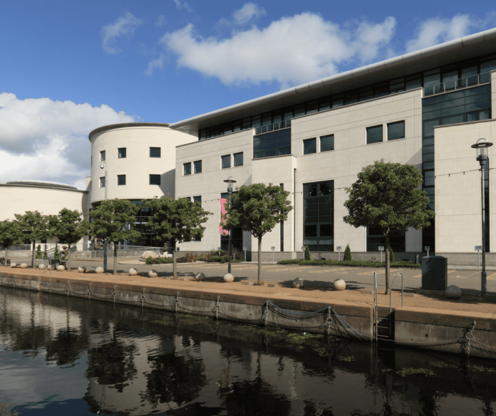 Modern waterfront self-storage solutions building with glass and stone facade under a partly cloudy sky in the Greater Belfast Area.