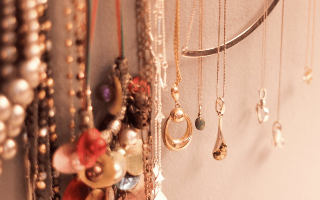 A collection of jewelry, including necklaces and earrings, displayed on a wall.