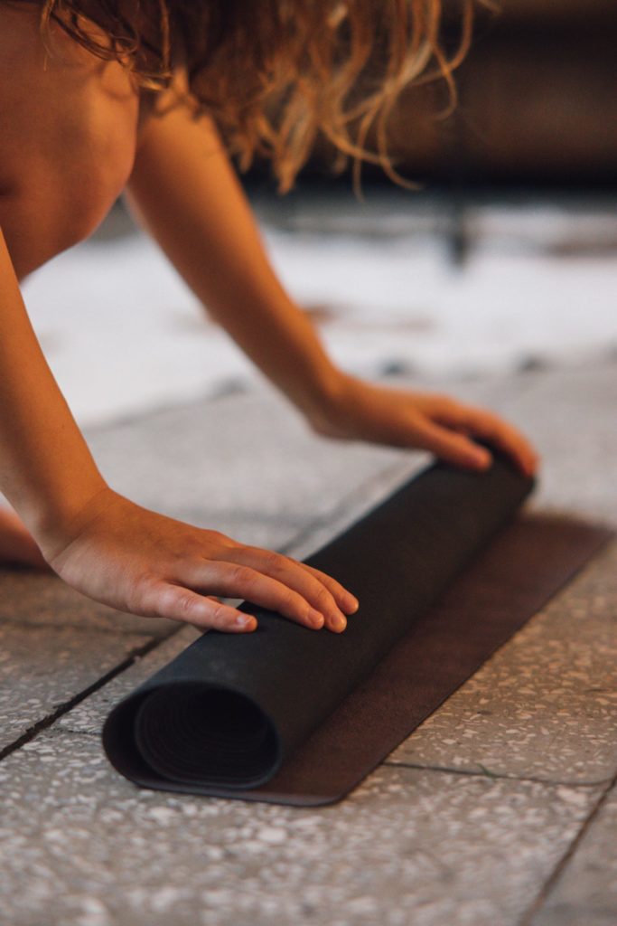 Person rolling out a yoga mat.