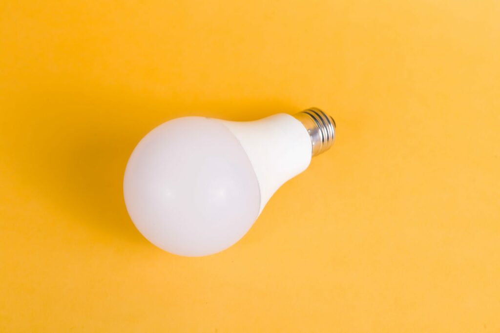 A white light bulb on a yellow background.